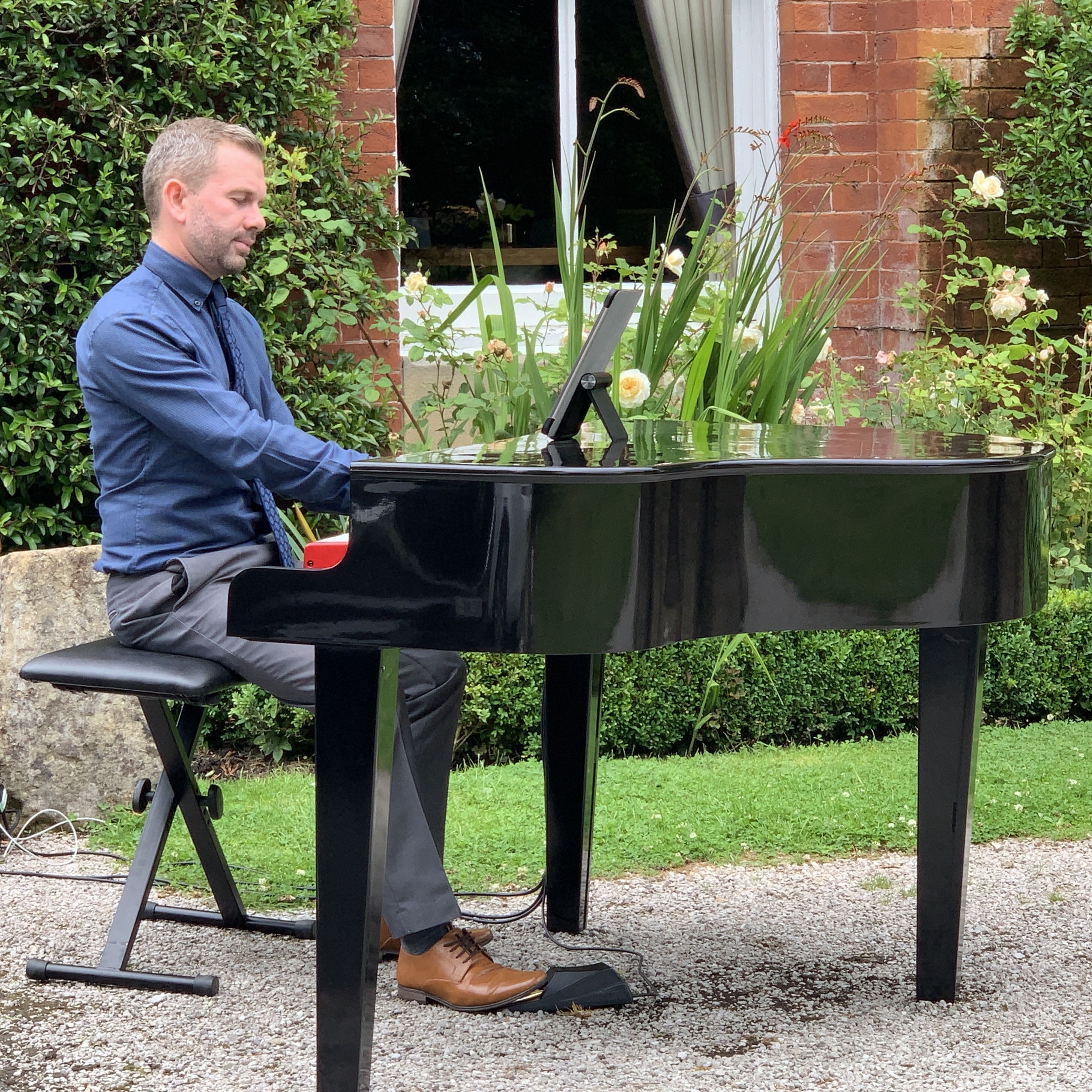 Wedding pianist Craig Smith plays his black baby grand piano for a drinks reception on the lawns
