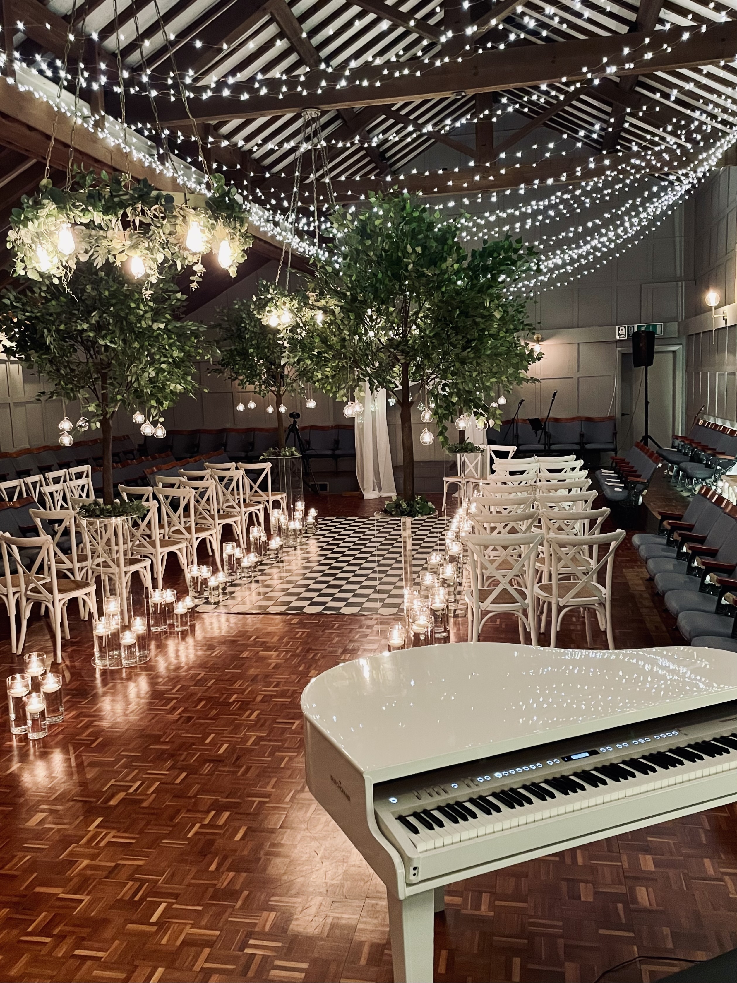 A Larkspur Lodge wedding ceremony set up with pianist Craig Smith's white grand piano reflecting the fairylit