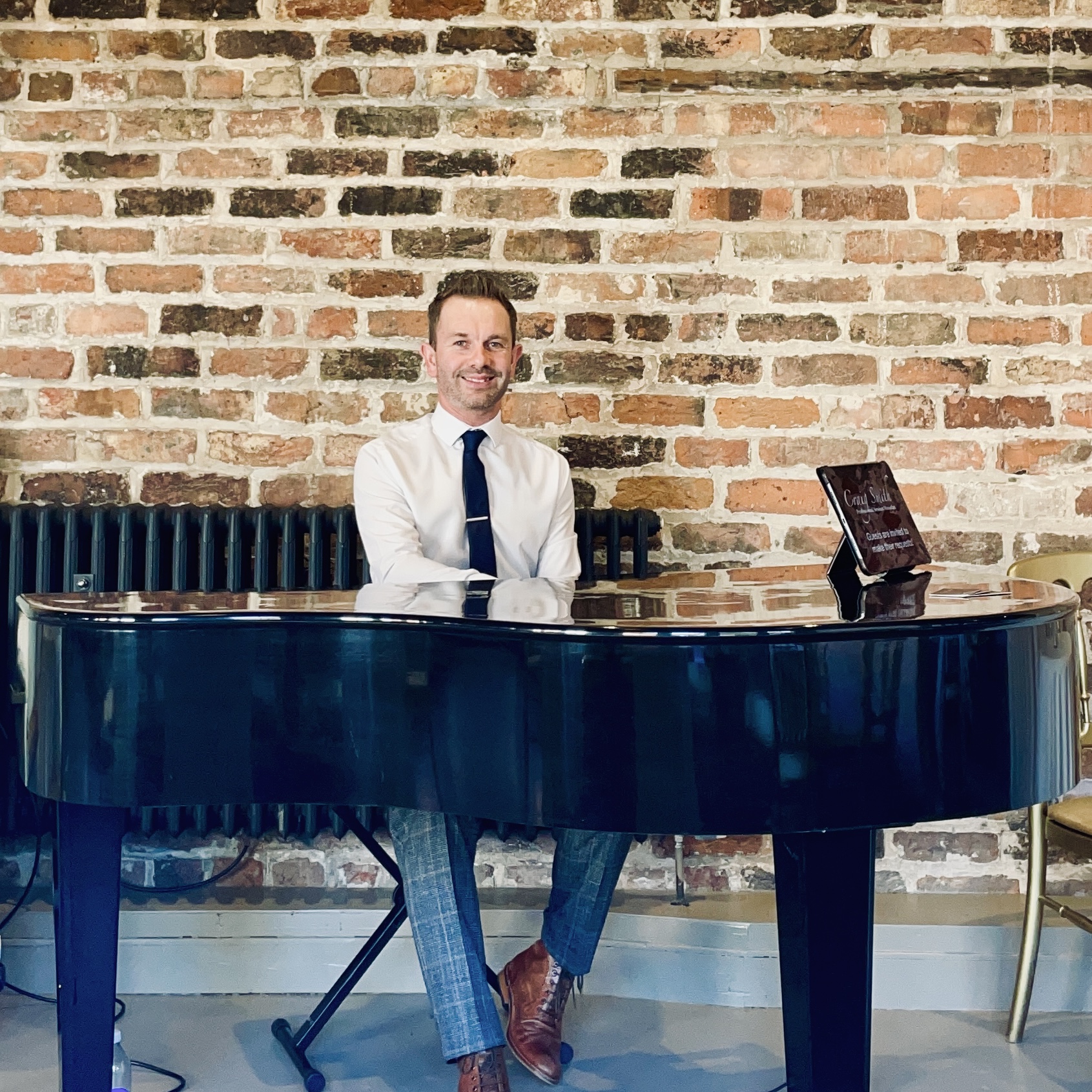 Wedding pianist Craig Smith performs during a Meols Hall wedding reception on a black baby grand piano in the Coach House