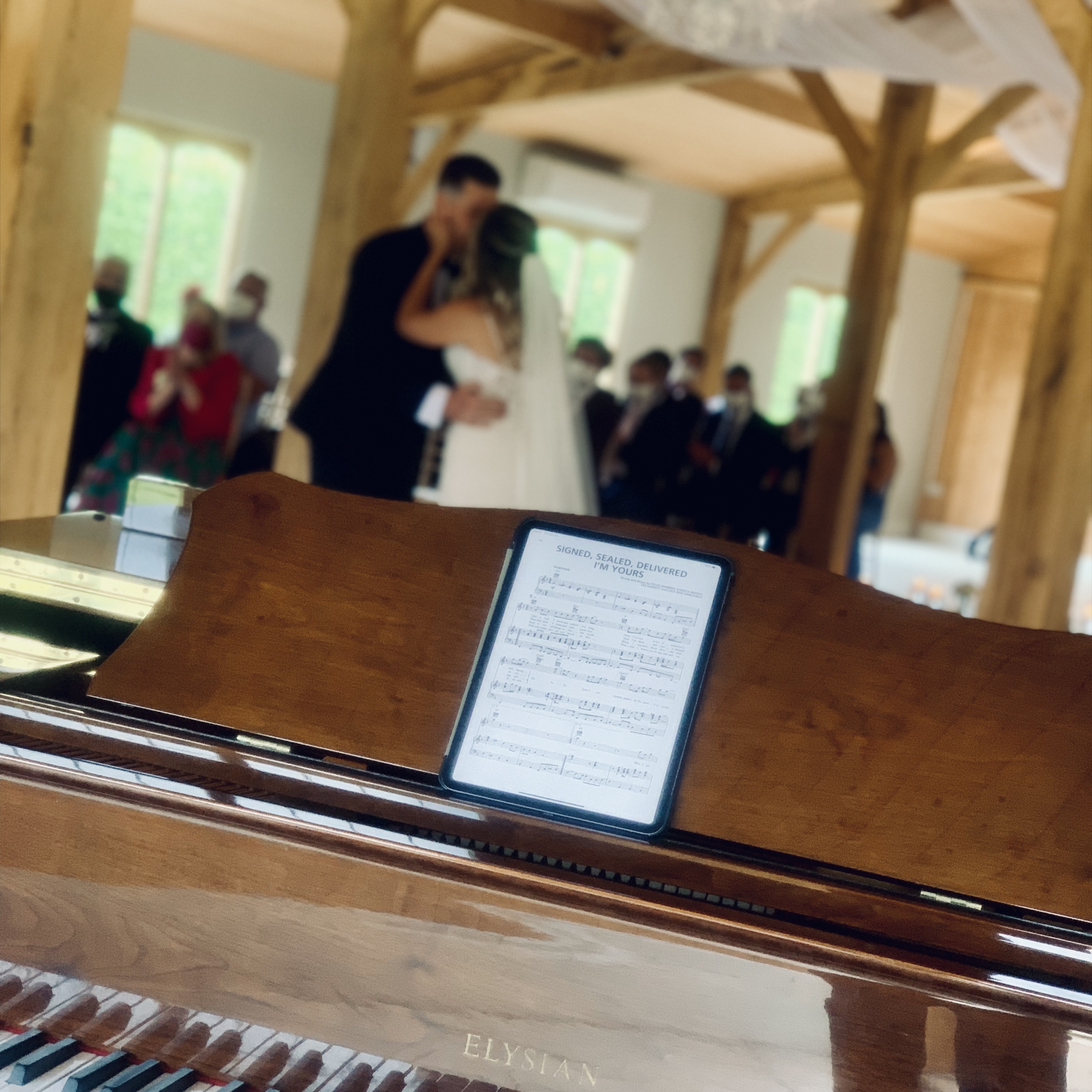 The bride and groom kiss following their Merrydale Manor wedding - seen from the piano where Craig Smith is performing