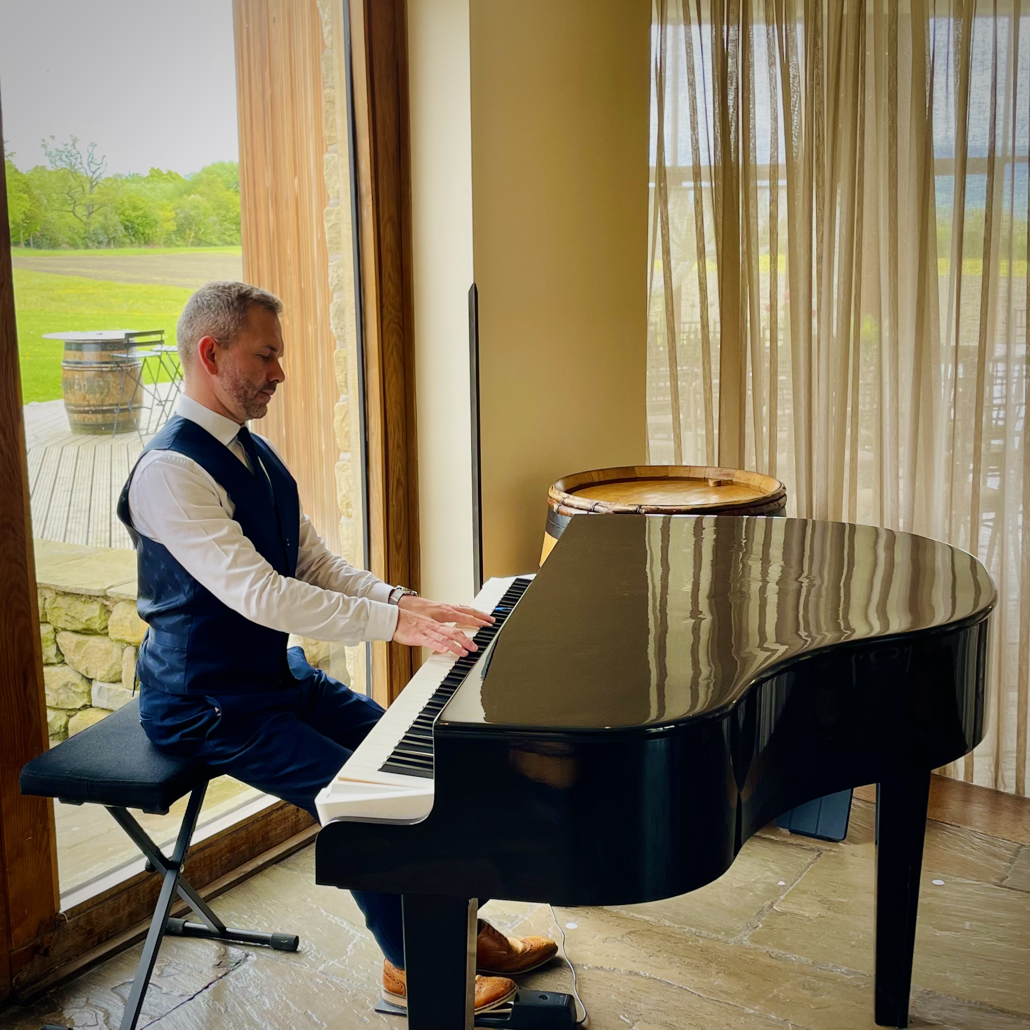 Out Barn wedding pianist Craig Smith plays his black baby grand piano during a drinks reception