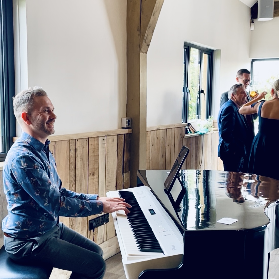 Wedding pianist Craig Smith playing his black baby grand piano during a River Barn wedding reception.