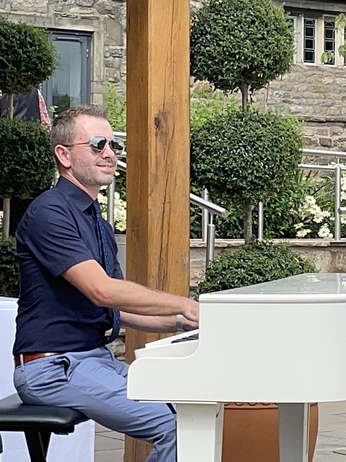 Craig Smith plays his white baby grand piano at a Stirk House wedding reception outside on the terrace