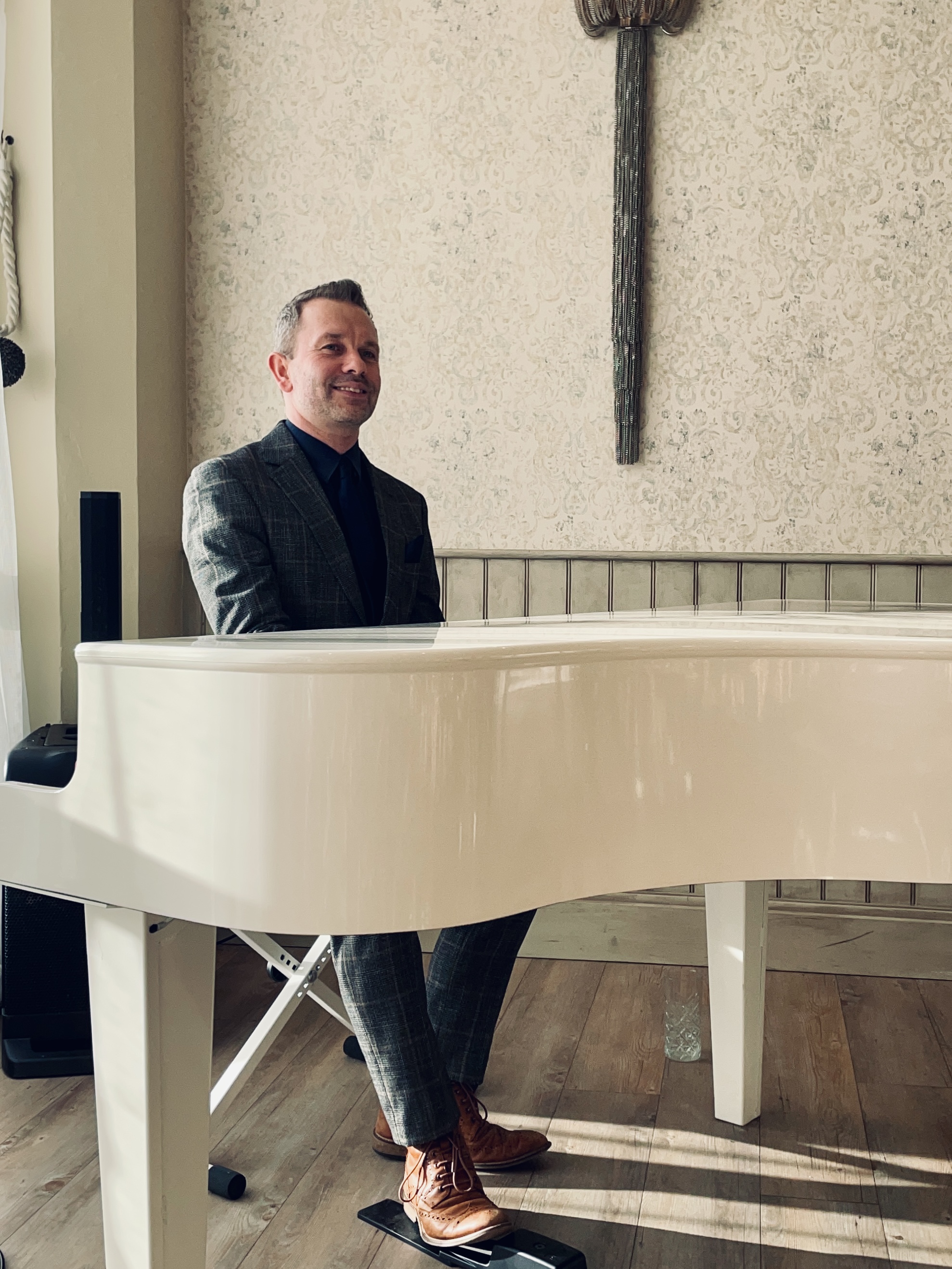 Craig Smith plays his white baby grand piano at a Wennington Hall wedding ceremony