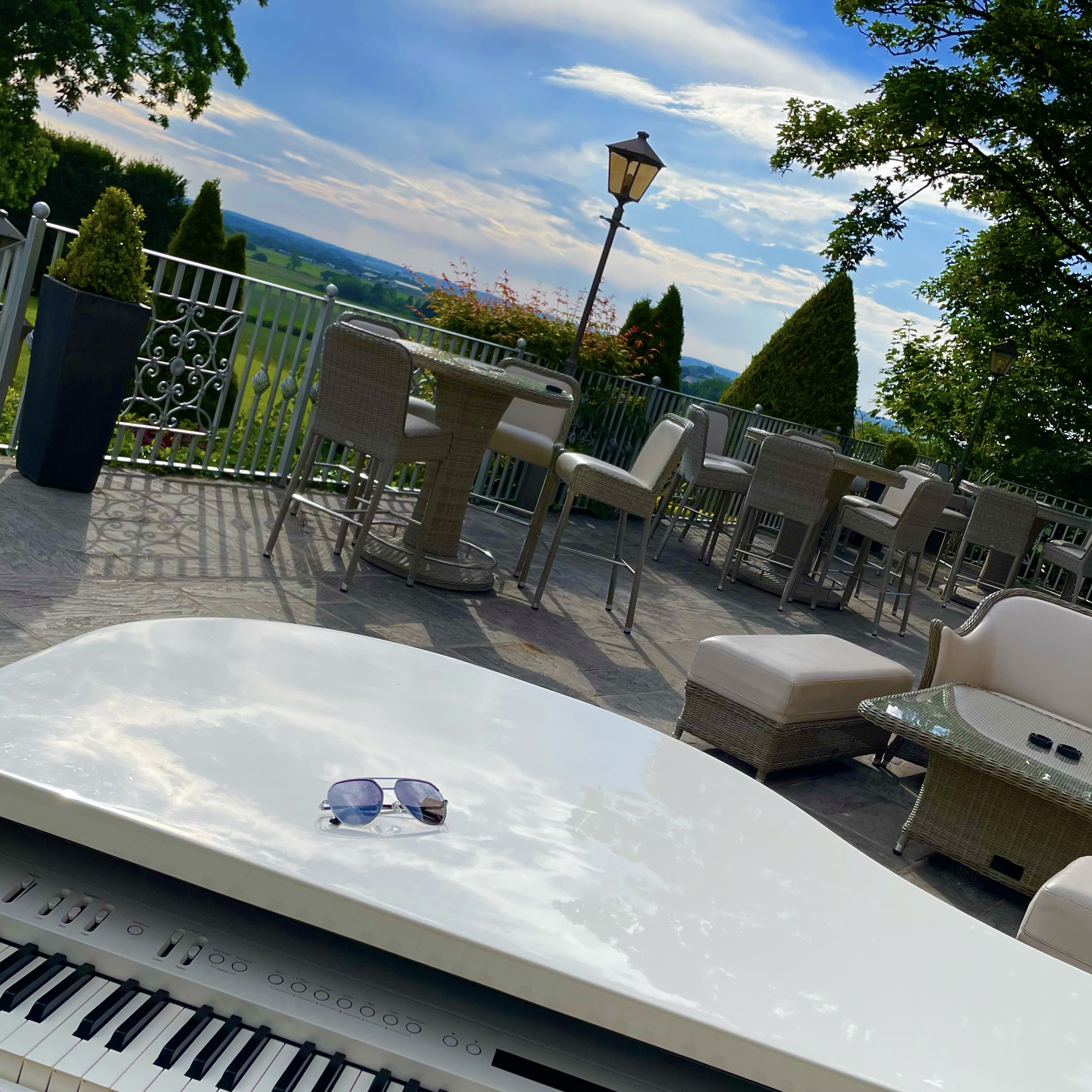 West Tower's recommended wedding pianist Craig Smith's white piano set up ready a stylish sunset drinks reception on the terrace