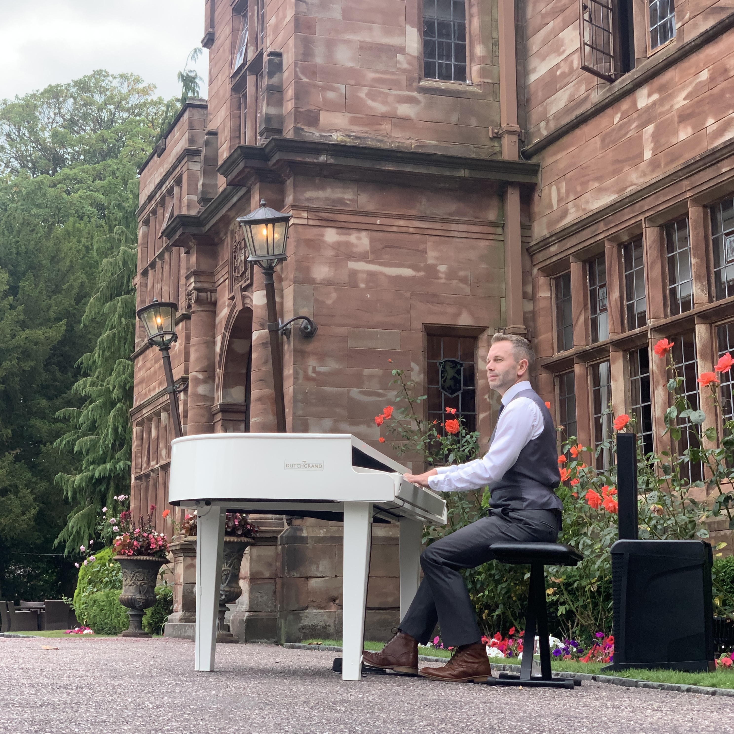 Wrenbury Hall pianist Craig Smith plays a white baby grand piano outside the venue