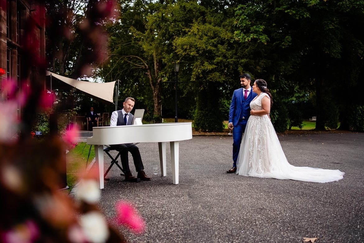 Wedding pianist Craig Smith playing piano at Wrenbury Hall as the bride and groom watch on