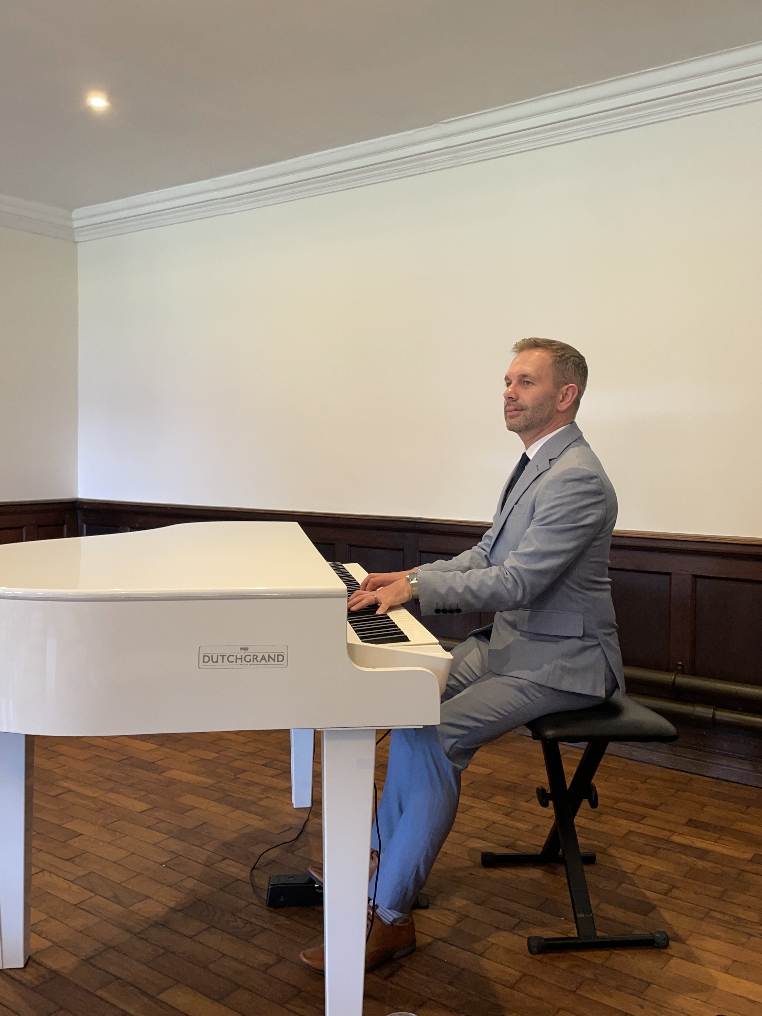 Craig Smith plays his white baby grand piano at a Wrenbury Hall wedding ceremony